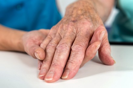 Ein Hand hilft einer anderen Hand einer Pantientin mit Demenz